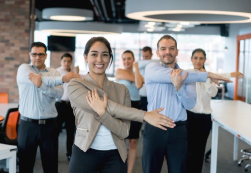 Employees performing yoga at a workplace wellness event 